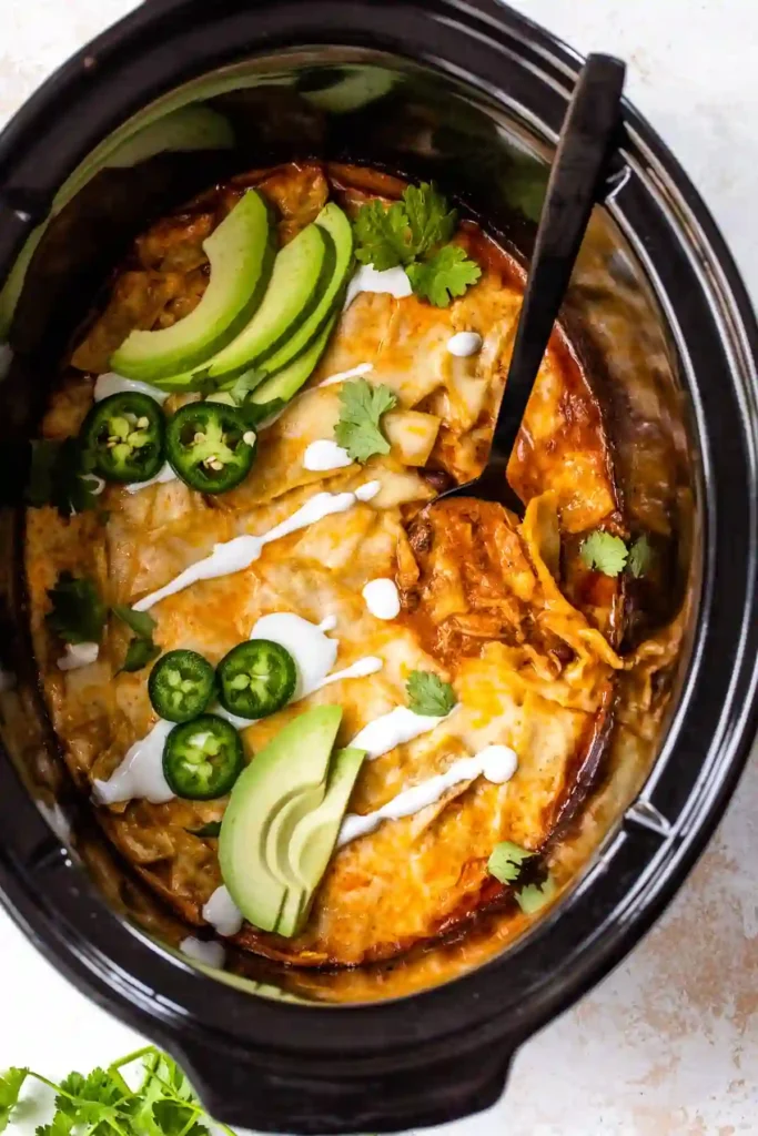 Slow Cooker Chicken Enchiladas 2 Slow cooker chicken enchiladas topped with melted cheese, avocado slices, jalapeños, and cilantro.