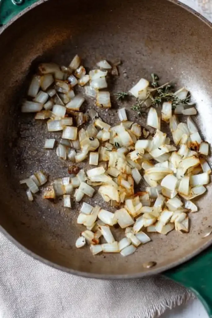 Slow Cooker Chicken Enchiladas 6 Onions sautéing in a skillet with herbs for Slow Cooker Chicken Enchiladas.