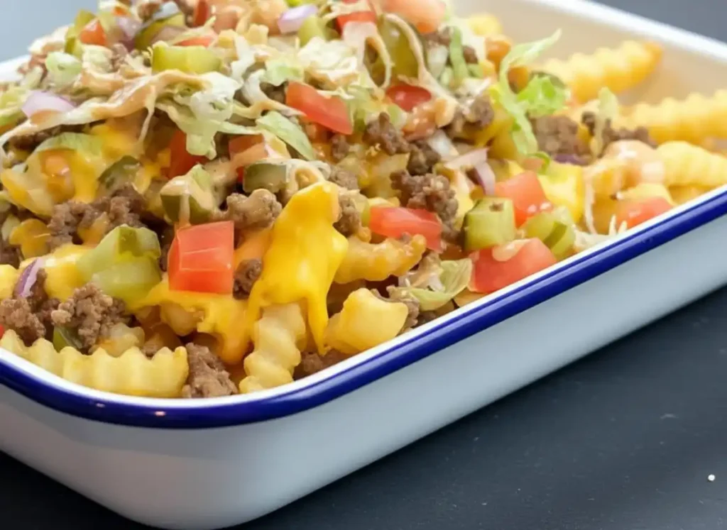 Amazing Cheeseburger Fries: Easy Recipe 5 A serving dish filled with cheeseburger fries layered with melted cheese, ground beef, tomatoes, pickles, lettuce, and special sauce.