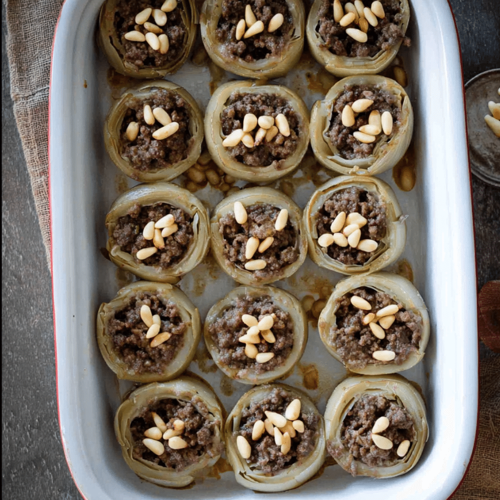 Stuffed Artichoke Bottoms Made Easy with One Great Recipe 15 Baked stuffed artichoke bottoms with ground beef and pine nuts in a serving dish.
