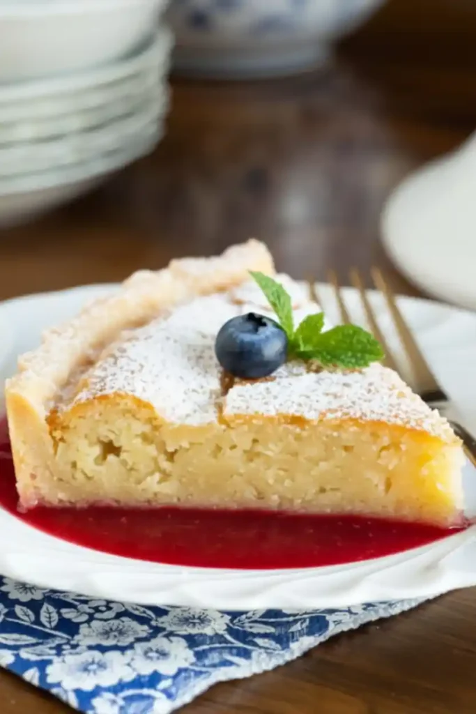 Frangipane Cake Recipe (Almond cake) 4 Frangipane Cake Recipe slice dusted with powdered sugar on raspberry sauce, garnished with a blueberry and mint.